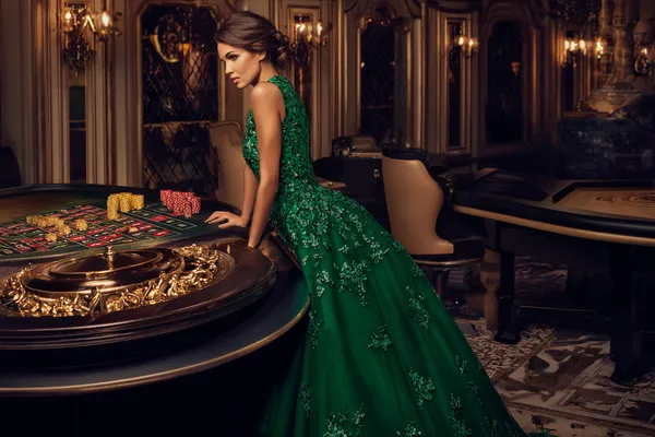 A woman in a luxurious green gown next to an ornate roulette wheel, capturing the upscale casino mood of BETPH7.